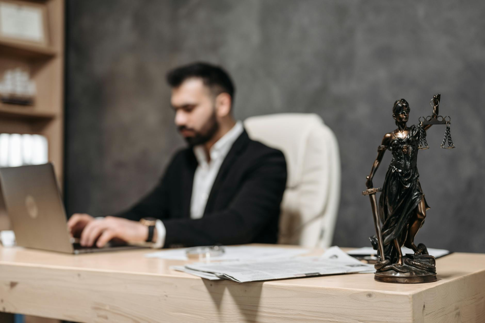 On-Page SEO for Law Firms: The - A businessman working on a laptop in an office with a Lady Justice statue in focus on the de