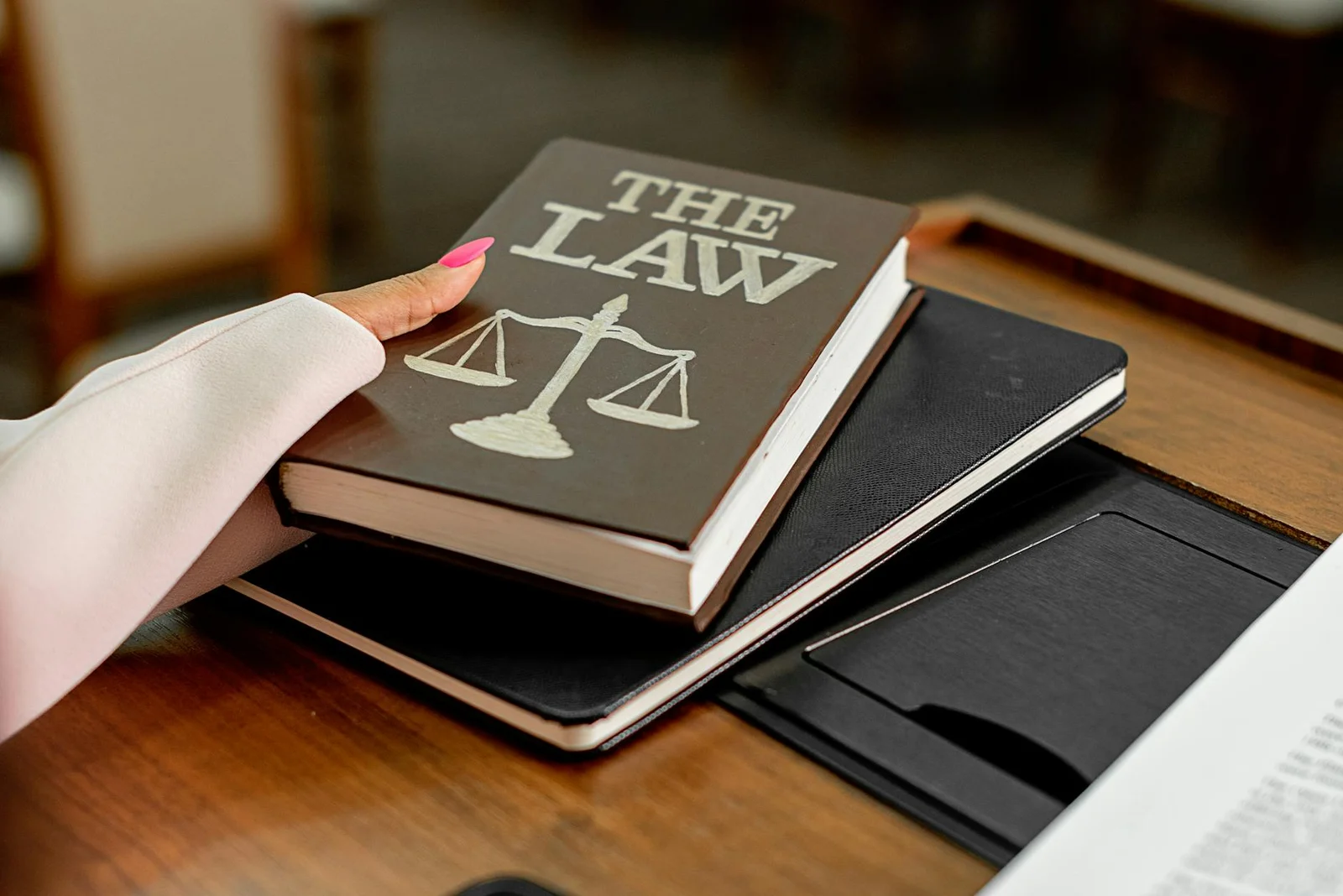 law firm keyword research - How - Closeup image of a law book titled 'The Law' on a wooden desk with scales of justice.